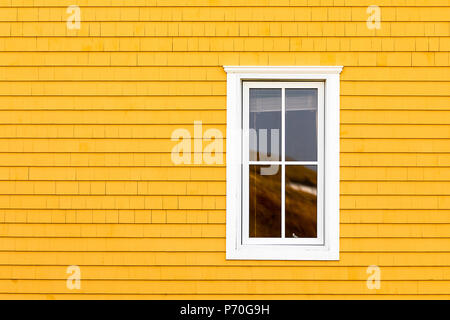 White window on yellow shingled wall. Typical colourful architecture of Iles de la Madeleine in Canada. Space for your text. Stock Photo