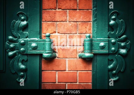 Symmetrical ornate metal hinges with red brick wall and vignette. Traditional style door detail in Berlin, Germany. Space for your text. Stock Photo