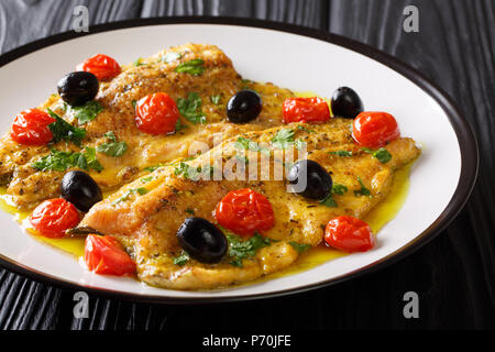 Mediterranean cuisine: fried trout fillets with garlic lemon butter sauce, tomatoes, parsley and olives close-up on a plate on a table. horizontal Stock Photo