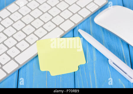 closeup shot of empty note paper, pen, computer keyboard and mouse on blue wooden surface Stock Photo