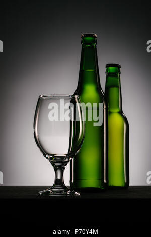 close up view of bottles of beer and empty glass on grey background Stock Photo