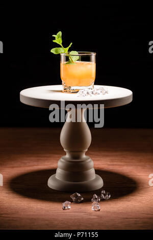 alcohol cocktail with mint and ice cubes on cake stand on table Stock Photo