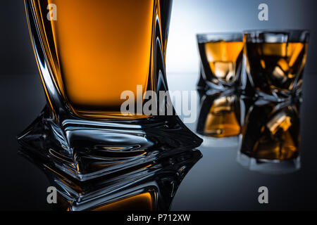 selective focus of cognac bottle and two glasses, on grey Stock Photo