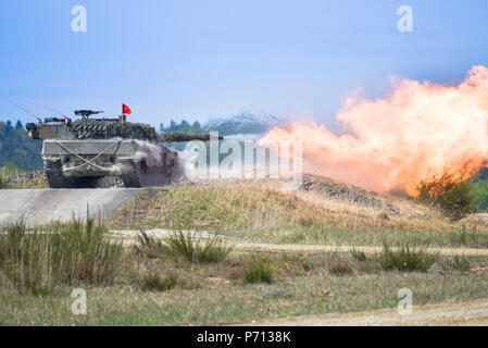 An Austrian Leopard 2A4 tank fires at its target during the Strong Europe Tank Challenge (SETC), at the 7th Army Training Command Grafenwoehr Training Area, Germany, May 11, 2017. The Strong Europe Tank Challenge (SETC) is co-hosted by U.S. Army Europe and the German Army, May 7-12, 2017. The competition is designed to project a dynamic presence, foster military partnership, promote interoperability, and provides an environment for sharing tactics, techniques and procedures. Platoons from six NATO and partner nations are in the competition. Stock Photo