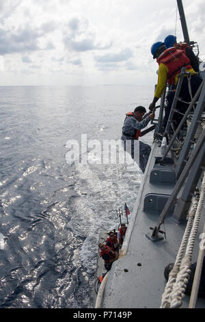 SOUTH CHINA SEA (May 11, 2017) Sailors aboard Arleigh Burke-class guided-missile destroyer USS Sterett (DDG 104) conduct a personnel transfer with Royal Thai Navy ship HTMS Naresuan (FFG 421) and Republic of Singapore ship RSS Intrepid (FFS 69) in support of the Cooperation Afloat Readiness and Training (CARAT) multilateral exercise. CARAT is a series of annual maritime exercises aimed at strengthening partnerships and increasing interoperability through bilateral and multilateral engagements ashore and at sea. Stock Photo