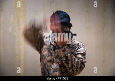 U.S. Marine Sgt. Brent Serquina assigned to 1st Platoon, Bravo Company, 9th Engineer Support Battalion, 3D Marine Logistics Group, puts on his gas mask to prepare for a Military Operation Urban Terrain drill on Camp Hansen, Okinawa, Japan, May 11, 2017. This training was conducted to increase the Marines’ tactical proficiency in a combat environment. Stock Photo