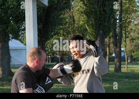 Sgt. 1st Class Joel Vallete, signal section chief of Headquarters Company, 1st Battalion, 8th Infantry Regiment, 3rd Armored Brigade Combat Team, 4th Infantry Division, conducts boxing mitt drills with one of his trainees on May 11, 2017 at Mihail Koglanicenau Air Base, Romania. Vallete, an All Army Boxing coach, uses boxing as a constructive way to spend free time with his fellow soldiers while on deployment in Romania, as well as sharing a passion of his with others. Stock Photo