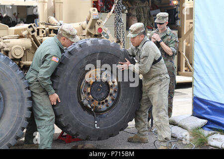 Pfc. Corey Smith, left, of Littleton, Colorado, and Pvt. Daniel Hernandez, of San Jose, California, both M1A2 Abrams main battle tank system maintainers with 64th Brigade Support Battalion, 3rd Armored Brigade Combat Team, 4th Infantry Division, remove a tire from a palletized load system while conducting maintenance at the Dragonkasernen, Denmark, May 11, 2107. The Soldiers are preparing vehicles to support a tank team from the brigade’s 1st Battalion, 66th Armor Regiment, at the Nordic Tank Challenge competition from May 15-18. Stock Photo
