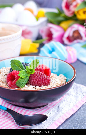 Sweet breakfast with aromatic coffee and muesli with berries. Fresh spring flowers. Yellow and pink tulips. Colored eggs for easter Stock Photo