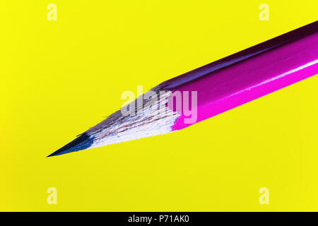 Cheap sharp sharpened pencil on a yellow background. Closeup. Stock Photo