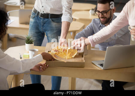 Happy colleagues enjoying shared pizza lunch in office together Stock Photo