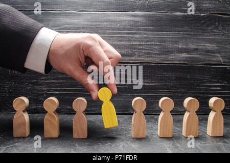 hand of a businessman takes a wooden figure of a man. The concept of search, hiring and firing workers, promotion. Business tactics and strategy, mana Stock Photo