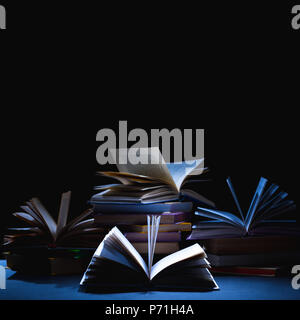 stack of different books on dark tabletop on black Stock Photo