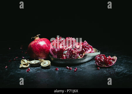 pomegranates in metal bowl and walnuts on a table Stock Photo