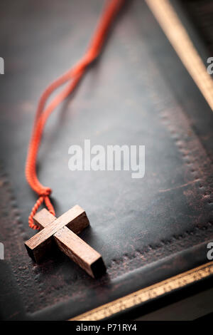 Closeup of simple wooden Christian cross necklace on holy Bible with copy space Stock Photo