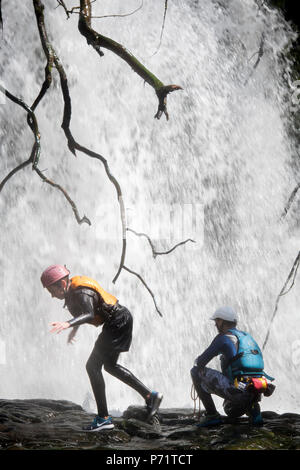 An instructor supervises a group gorge walking with Adventure Wales on the River Mellte near Pontneddfechan in the Brecon Beacons UK Stock Photo