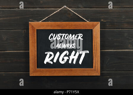 Board with lettering customer always right hanging on wooden wall Stock Photo