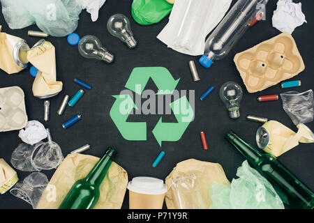 top view of various types of trash around recycle sign on black Stock Photo