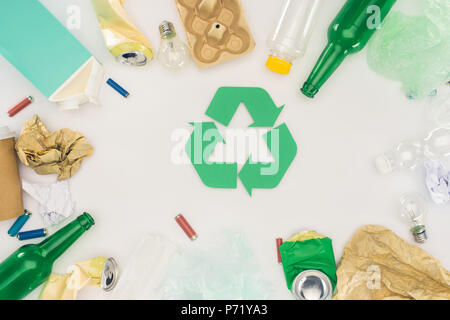 top view of various types of trash surrounding recycle sign on white Stock Photo