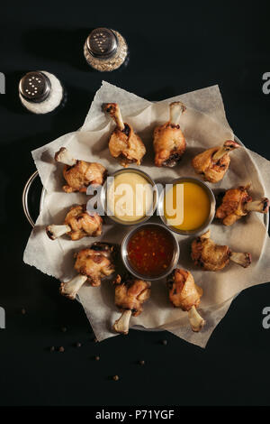 top view of delicious roasted chicken with various sauces on baking paper and spices in black Stock Photo