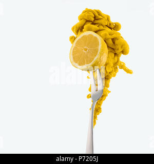 half of lemon on fork and yellow ink isolated on white Stock Photo