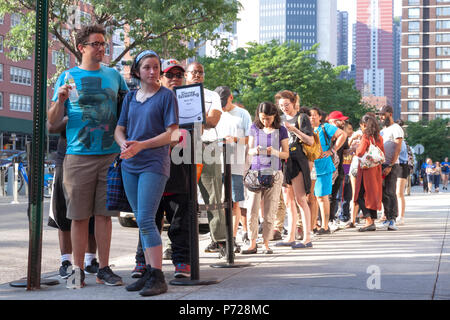 People standing in a line outside of a movie theater waiting to get in. Stock Photo