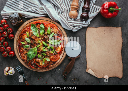 top view of delicious pizza with cutter and blank paper on concrete table Stock Photo