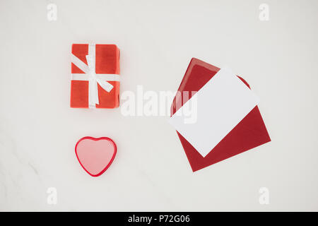 top view of opened red envelope with blank paper and gift boxes isolated on white Stock Photo