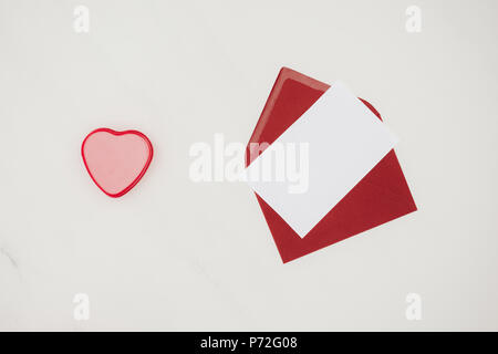 top view of red envelope with blank paper and heart shaped box isolated on white Stock Photo