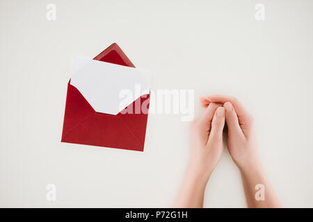cropped shot of woman holding hands near opened red envelope with blank paper isolated on white Stock Photo