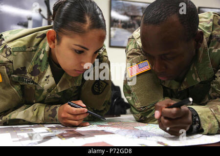 U.S. Army Pfc. Jessica Estrada and Sgt. Eric Taylor, both assigned to Headquarters and Headquarters Company (HHC) Network Enterprise Technology Command (NETCOM), plot their points during the land navigation training exercise for the NETCOM Best Warrior Competition at Fort Huachuca, Az., May 11, 2017. The land navigation training is designed to test the soldiers' abilities in teamwork and leadership as well as determining the grid coordinates on a military map. Stock Photo