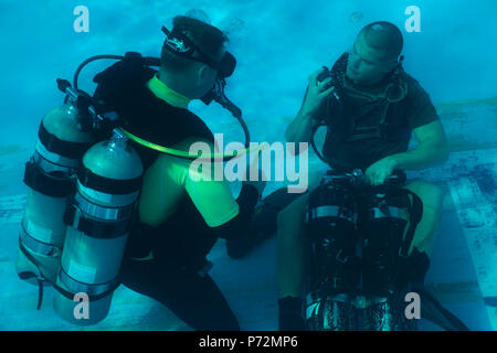 Cpl. Drake Johnson, right, adjusts his scuba gear after being disoriented by an instructor during a portion of the United States Marine Corps Combatant Divers Course, on Camp Schwab, Okinawa, Japan, May 11, 2017. The USMC Combatant Divers Course is eight weeks and combines lectures, demonstrations and practical application of circuit diving, diving physics and medical aid. Johnson, from Mitchell, South Dakota, is a reconnaissance Marine with 3rd Reconnaissance Battalion, 3rd Marine Division, III Marine Expeditionary Force. Stock Photo