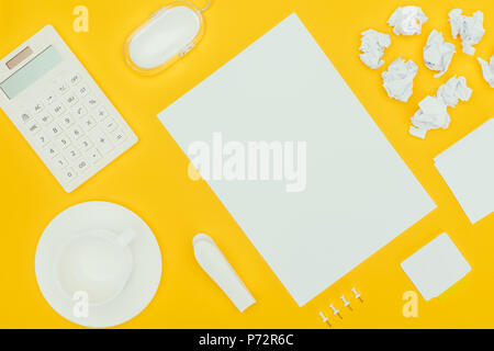 top view of blank sheet of paper, crumpled papers, notes, calculator and computer mouse isolated on yellow Stock Photo