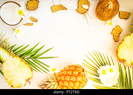 Summer flat lay scene with tropical fruits pineapples and coconuts on gray wooden background, toned Stock Photo