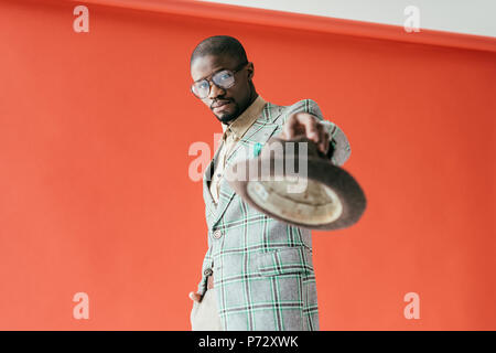 selective focus of handsome african american man posing with hat, on red Stock Photo