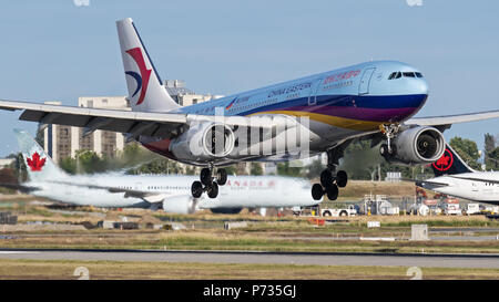 Richmond, British Columbia, Canada. 2nd July, 2018. A China Eastern Airlines Airbus A330-200 (B-5943) wide-body jet airliner landing at Vancouver International Airport. In the background: Air Canada jets on the tarmac. Credit: Bayne Stanley/ZUMA Wire/Alamy Live News Stock Photo