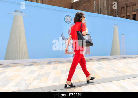 Battersea Power Station, London, 4th July 2018. Art Night photocall. Artist Cecile B. Evans walks along the 80 metre long mural. Art Night and Hayward Gallery unveil South London based artist Suzanne Treister’s new colourful, large-scale 80 metre outdoor mural wrapped around the hoardings at Battersea Power Station ahead of the one-night only festival 'Art Night 2018' on Saturday 7 July. k, Vauxhall and Nine Elms. Credit: Imageplotter News and Sports/Alamy Live News Stock Photo