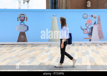 Battersea Power Station, London, 4th July 2018. Art Night photocall. An Art Night organiser walks along the 80 metre long mural. Art Night and Hayward Gallery unveil South London based artist Suzanne Treister’s new colourful, large-scale 80 metre outdoor mural wrapped around the hoardings at Battersea Power Station ahead of the one-night only festival 'Art Night 2018' on Saturday 7 July. k, Vauxhall and Nine Elms. Credit: Imageplotter News and Sports/Alamy Live News Stock Photo