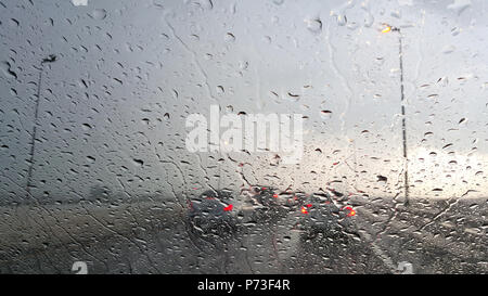 Inside the car. Closeup rain water drops. car windshield view during rainy day on highway in the evening Stock Photo