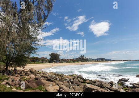 Florianopolis, Santa Catarina, Brazil. View of beach with rocks and trees in the foreground and village in the background on sunny summer day. Stock Photo