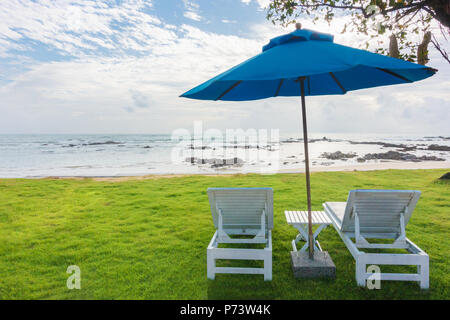 Pair of sun loungers and a beach umbrella on a deserted beach, Perfect vacation concept Stock Photo