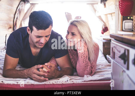 caucasian couple in love and romantic scene inside an old vintage camper ready to travel and have a vacation together with happiness and joy. blonde b Stock Photo