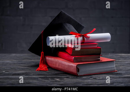 Stack of books with diploma and graduation hat on table Stock Photo