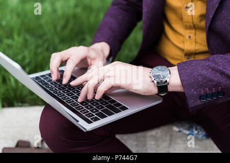 Close-up view of male hands with watch typing on laptop keyboard Stock Photo