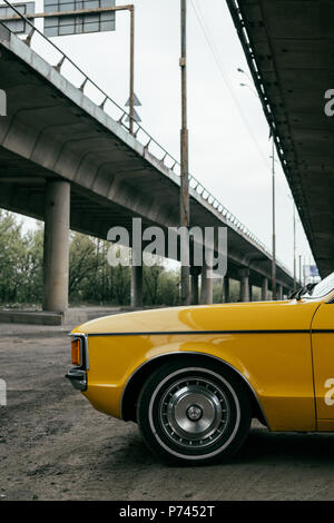 side view of yellow retro classic car under bridge Stock Photo