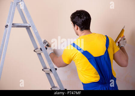 Young contractor employee applying plaster on wall Stock Photo