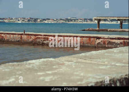 Rusty old iron mooring bollards, mounted on a concrete pier in the background. Stock Photo