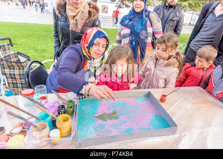 Unidentified woman teaches kid Ebru art or marbling. Traditional Turkish art in process in Istanbul, Turkey.09 April 2017 Stock Photo