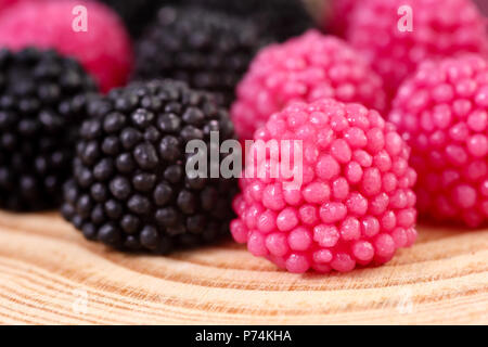 Extreme close up of raspberry and blackberry flavoured and shaped jelly drop candies on a wooden background Stock Photo