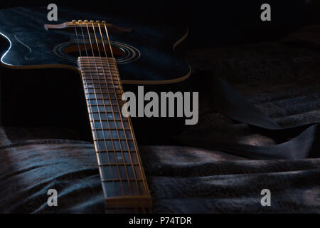 guitar laying in dark room with moonlight shining on it Stock Photo